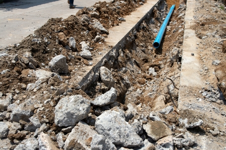 Excavation site with trench, stones, and a blue pipe