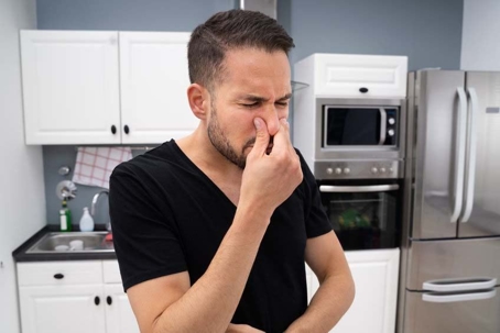 man smelling bad smell from drain